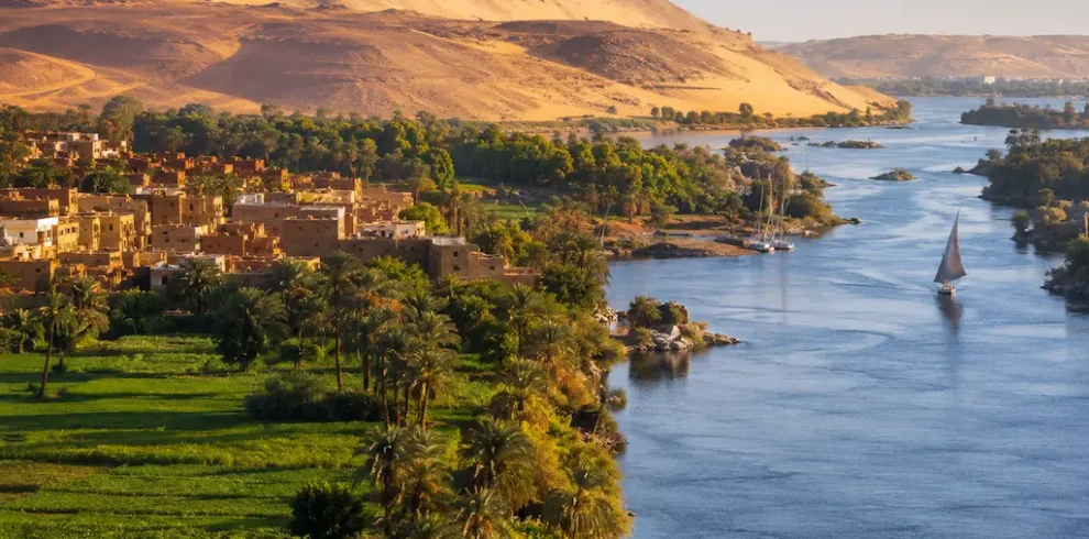 Nile Valley landscape with river, palm trees, farmland, and desert hills in Egypt