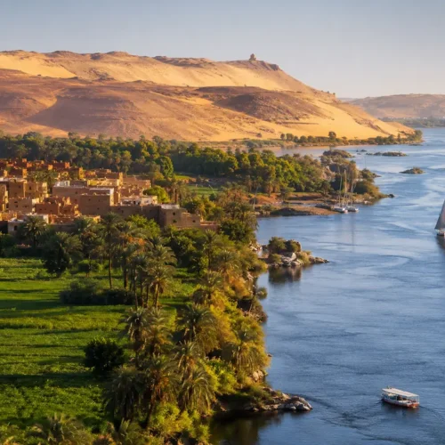 Landschaft im Niltal mit Fluss, Palmen, Feldern und Wüstenhügeln in Ägypten