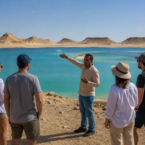 Reiseleitung mit Reisenden an einem türkisfarbenen See vor Wüstenhügeln in Fayoum