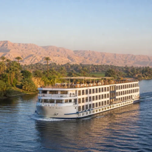 Nilkreuzfahrtschiff vor palmengesäumten Ufern in Oberägypten